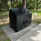 Black metal cabinet on a gravel surface with trees in the background