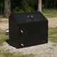 Black metal trash bin with multiple compartments on a gravel surface with trees in the background