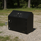 Black metal safe box on a gravel surface with trees in the background