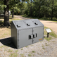 Gray outdoor trash bin with three compartments in a park setting