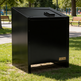 Black metal trash can with 'Taimco' branding in a park setting