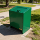 Green trash bin on a sidewalk in a park