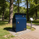 Blue trash bin in a park setting with trees and a pathway.
