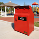 Red trash bin with 'trash' label in a park setting