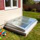 Skylight installed on a house exterior with toys on the grass