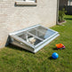 Skylight installed on a house exterior with toys and a ball on the grass.