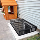 Powder‑coated steel window well grate with welded round‑bar grid and reinforced frame for basement safety and ventilation.