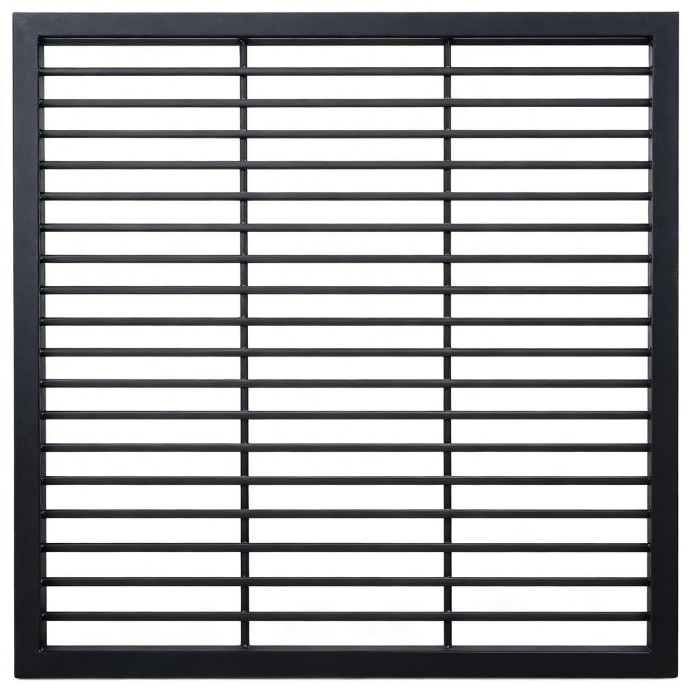 Black steel round‑bar window well grate installed beside a stone exterior wall with surrounding landscaping.