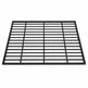 Black steel round‑bar window well grate installed beside a stone exterior wall with surrounding landscaping.